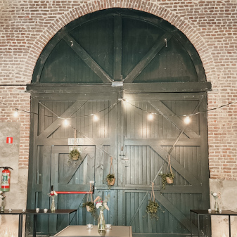 de grote groene achterdeur van eventschuur met daarvoor staantafels